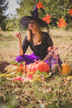 Cadılar Bayramı cadısı Mistik atmosferdeki kadın balkabağıyla dışarıda sonbaharı kutluyor.