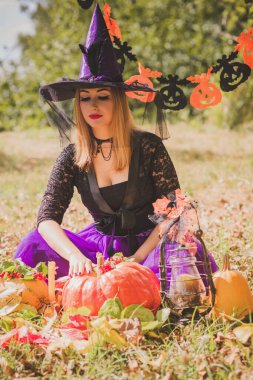 Cadılar Bayramı cadısı Mistik atmosferdeki kadın balkabağıyla dışarıda sonbaharı kutluyor.