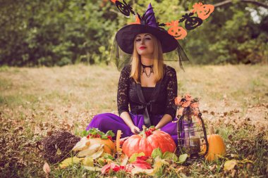 Cadılar Bayramı cadısı Mistik atmosferdeki kadın balkabağıyla dışarıda sonbaharı kutluyor.