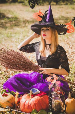 Cadılar Bayramı cadısı Mistik atmosferdeki kadın balkabağıyla dışarıda sonbaharı kutluyor.