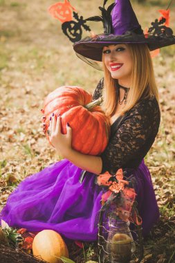 Cadılar Bayramı cadısı Mistik atmosferdeki kadın balkabağıyla dışarıda sonbaharı kutluyor.