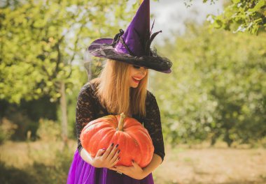 Cadılar Bayramı cadısı Mistik atmosferdeki kadın balkabağıyla dışarıda sonbaharı kutluyor.