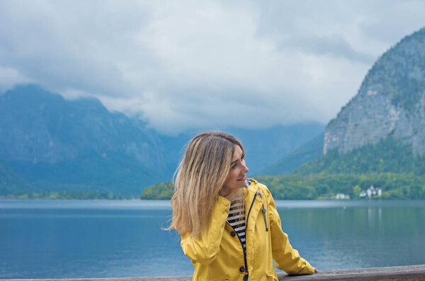 Woman in Yellow Jacket Admiring Hallstatt Lake, Austria. Travel and Tourism Concept in Scenic Alpine Village