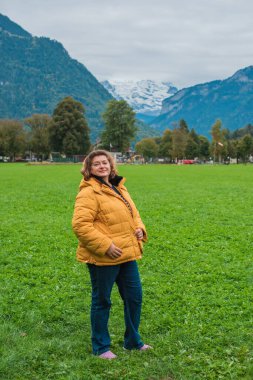 Avrupa 'da Olgun Kadın. Sonbahar Yaşam Tarzı Konsepti. Kalın sonbahar kıyafetleri giymiş şık, kilolu bir bayan, günlük kıyafetler. Yaşam tarzı ve seyahat konsepti vücut pozitifliği, kendine güven gösteriyor
