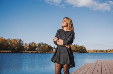 Sonbaharda parkta yürüyen Avrupa ve Ortadoğu görünümlü modern bir kadın. Şık mevsimlik kıyafetler, ılık ışık ve sonbahar renkleri rahat bir yaşam tarzı yaratıyor..