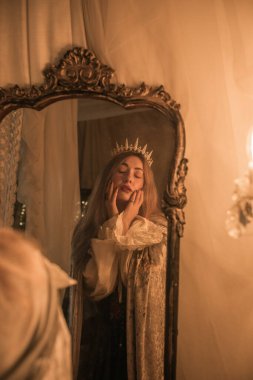 Queen in the Mirror. Emotional vintage warm portrait with candles around 