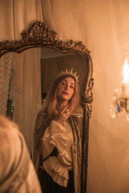 Queen in the Mirror. Emotional vintage warm portrait with candles around 