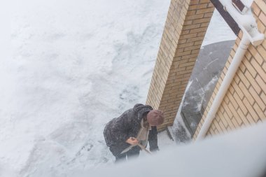 Kışın kar yağarken süpürgeyle derin kar temizliyorum. Kar yağışı, soğuk hava ve mevsimsel zorluklar kavramı