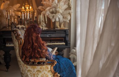 Karanlık Vintage Interior 'daki Baş Rahibe. 50 yaşında, kızıl saçlı, gizemli bakışlı zarif mavi dantelli elbisesi olan çekici bir kadının çarpıcı portresi.