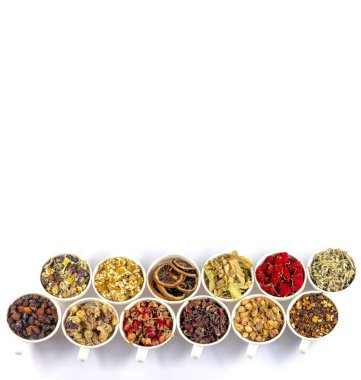 Beyaz arka planda fincanlarda çeşitli bitkisel çay malzemeleri var. Doğal bitkiler ilacı..