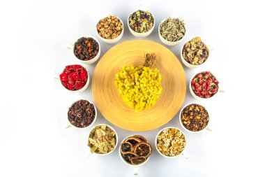 Beyaz arka planda fincanlarda çeşitli bitkisel çay malzemeleri var. Doğal bitkiler ilacı..