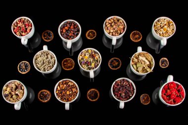 Beyaz arka planda fincanlarda çeşitli bitkisel çay malzemeleri var. Doğal bitkiler ilacı..