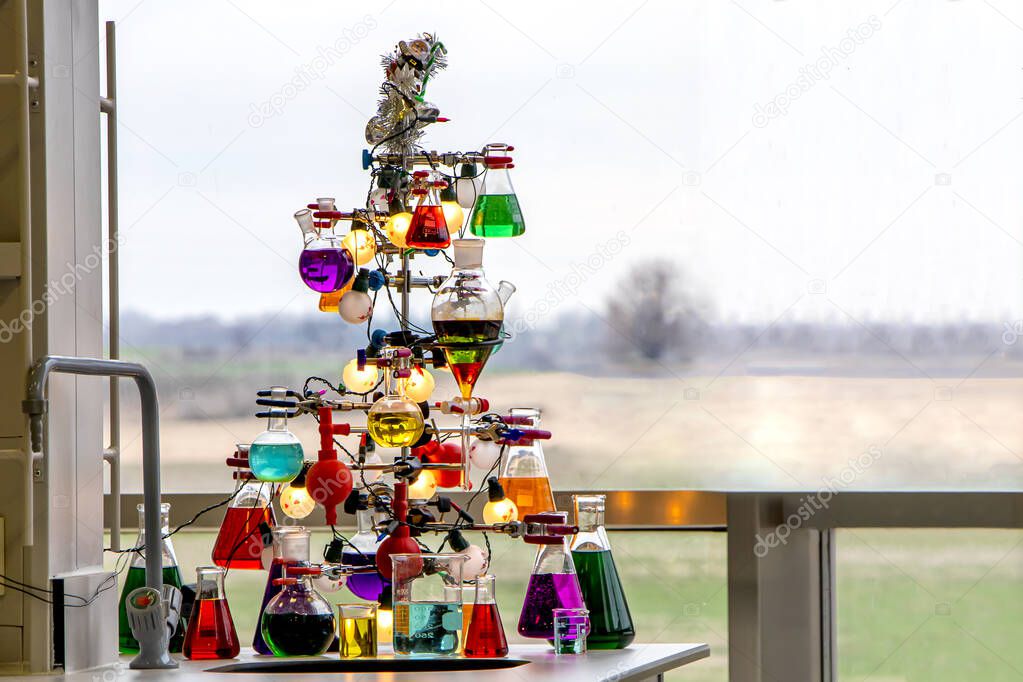 Christmas tree made of iron, filled tubes, conical flasks, erlenmeyer with colorful liquids used in chemistry. New year in the chemistry laboratory concept.