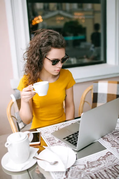 Joven chica beautidul con ordenador portátil y té en la cafetería al aire libre —  Fotos de Stock