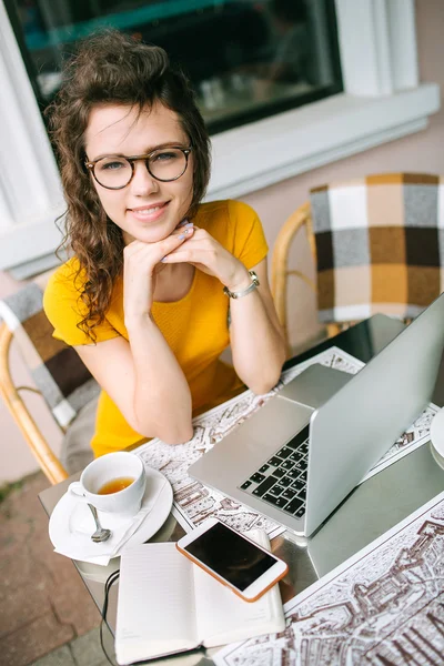 Girl in glasses with laptop and tea in cafe outdoors — Stock Photo, Image