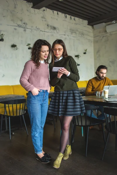 Two young females with smartphone and tablet in cafe — Stock Photo, Image