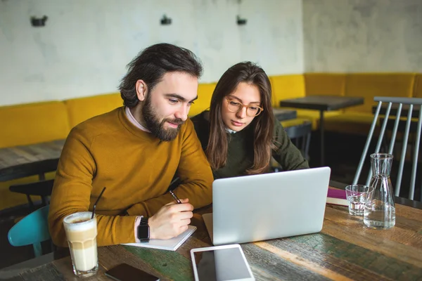 Yong hipster mâle et femelle dans un café travaillant avec un ordinateur portable — Photo