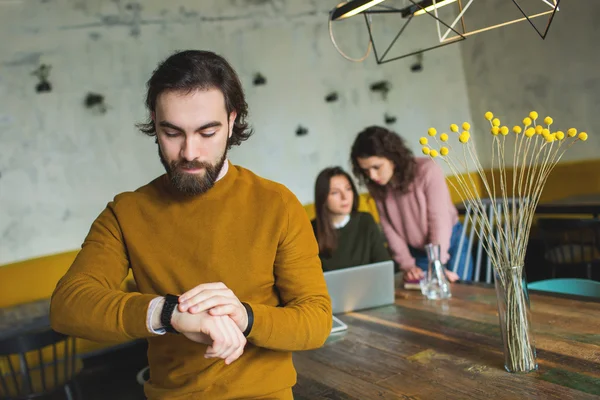 Joven hipster con reloj inteligente sobre dos mujeres en la cafetería —  Fotos de Stock