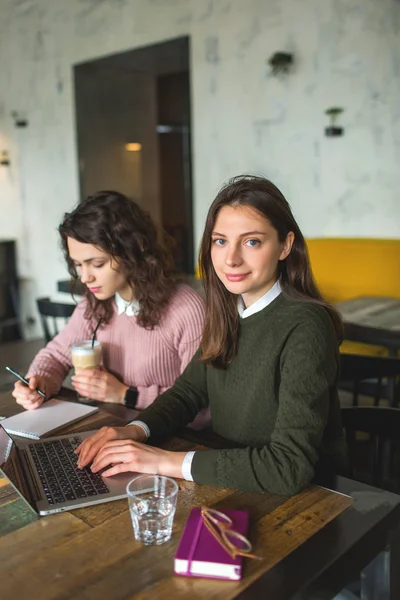 Jovens mulheres bonitas trabalhando com notas e laptop no café — Fotografia de Stock