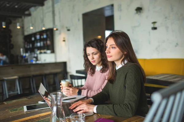 Jóvenes mujeres bonitas que trabajan con notas y portátil en la cafetería —  Fotos de Stock