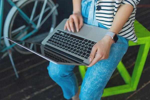 Young pretty woman with laptop on her knees in studio with bicyc — Stock Photo, Image