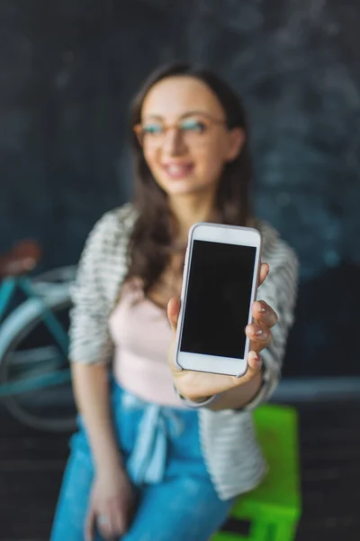 Young pretty woman showing smartphone in her hand taking picture — Stock Photo, Image