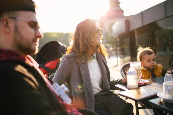 Kávézó napsütéses napon a szabadban-boldog fiatal család — Stock Fotó