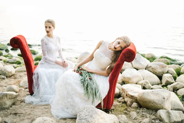 Hermanas gemelas en vestido de novia en la orilla del mar —  Fotos de Stock