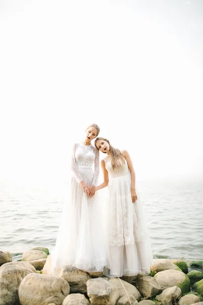 Hermanas gemelas en vestido de novia en la orilla del mar —  Fotos de Stock