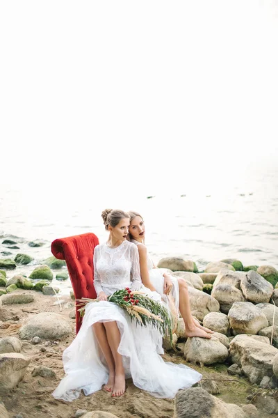 Twin sisters in wedding dress on the seashore — Stock Photo, Image