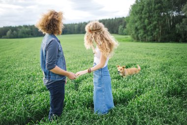 Genç güzel hippi çift yeşil yaz alanına yürüyor