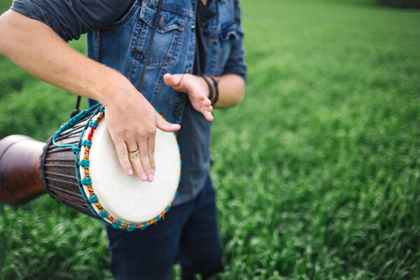 Мужчина играет на этническом барабане на улице
