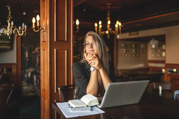 Femme dans un café avec ordinateur portable prenant des notes — Photo