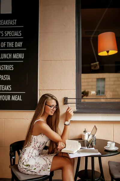 Жінка в кафе з ноутбуком приймає нотатки — стокове фото