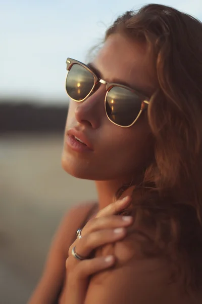 Joven hermosa mujer con el pelo largo y rizado en la playa bajo la puesta de sol de la noche —  Fotos de Stock