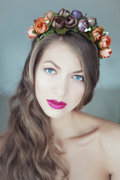 Porträt einer schönen Frau mit Blumen im Haar und blauen Augen — Stockfoto