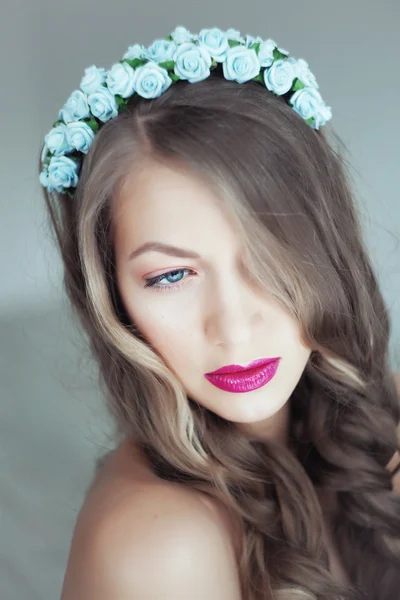 Portrait of beautiful woman with flowers in hair and blue eyes