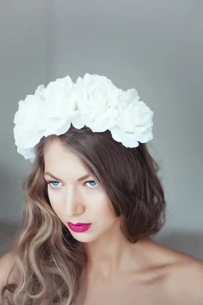 Porträt einer schönen Frau mit Blumen im Haar und blauen Augen — Stockfoto