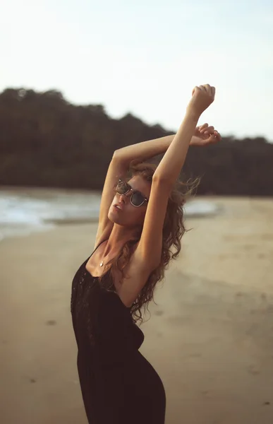 Young beautiful woman with long curly hair at the seaside under the evening sunset — Stock Photo, Image