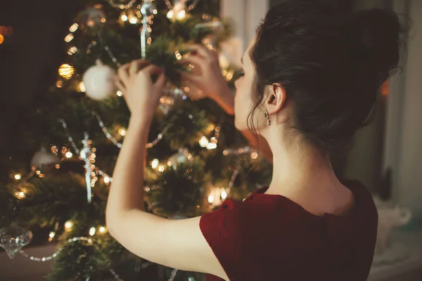 Женщина в красном платье на фоне рождественской елки — стоковое фото