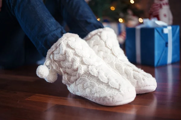 Pernas em meias quentes perto da árvore de Natal — Fotografia de Stock