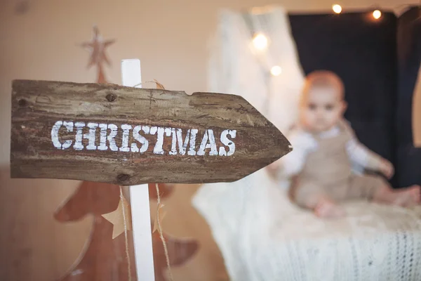 Bebé de Navidad sentado en una silla en un ambiente decorado — Foto de Stock