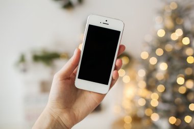 Beyaz smartphone ile arka planda Noel ağacı