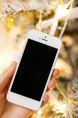 Beyaz smartphone ile arka planda Noel ağacı