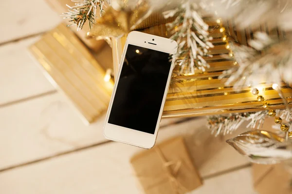 Smartphone blanco con el árbol de navidad en el fondo — Foto de Stock