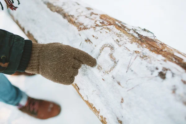 L'homme dessine le symbole du cœur sur la neige dans la forêt — Photo