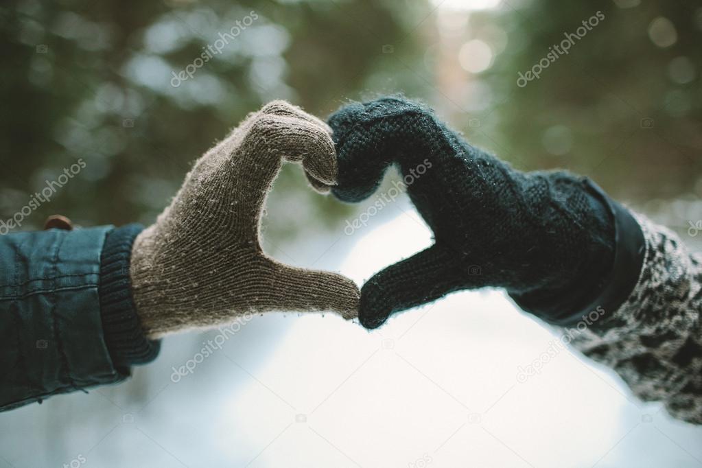 Two hands in gloves holding love heart symbol