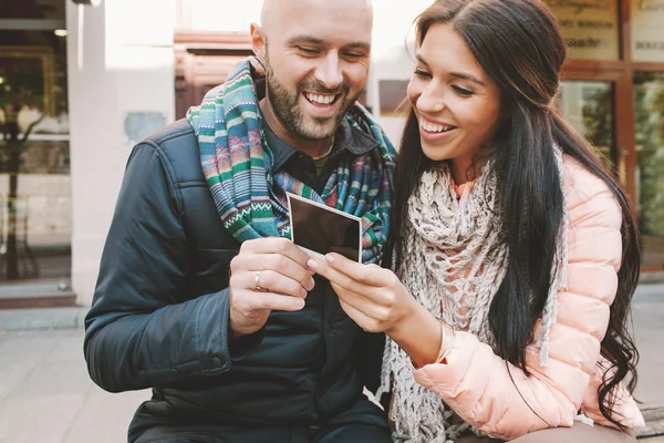 Young couple looking at polaroid picture in the city — Stock Photo, Image