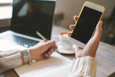 Elleri kalem ve Not Defteri ile smartphone cof ile tutan kadın