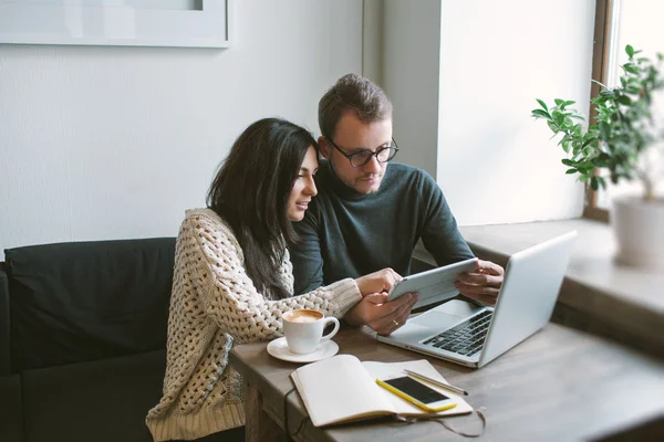 Couple travaillant dans un café avec tablette, ordinateur portable, smartphone, bloc-notes — Photo